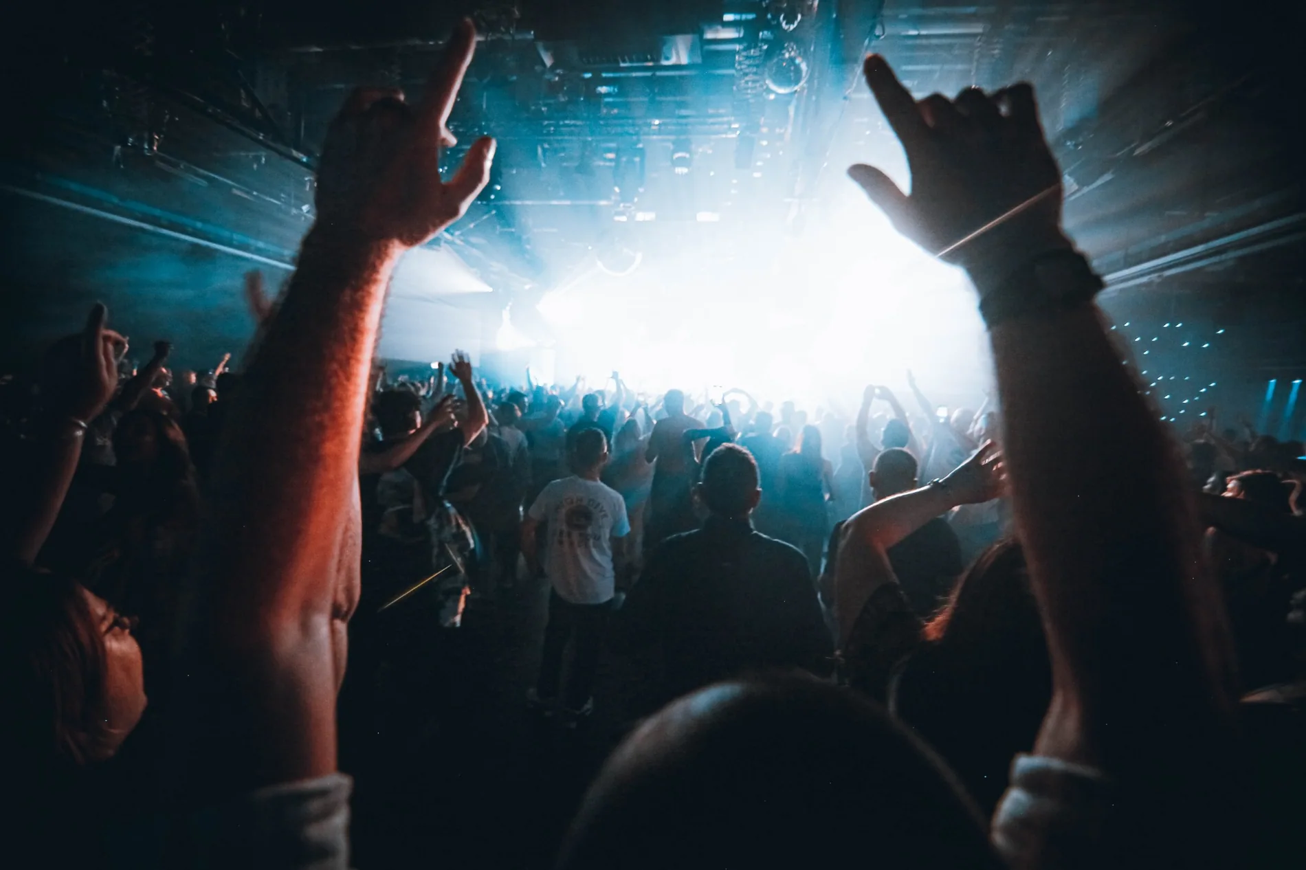 Live music crowd with raised hands and blue-white concert lighting