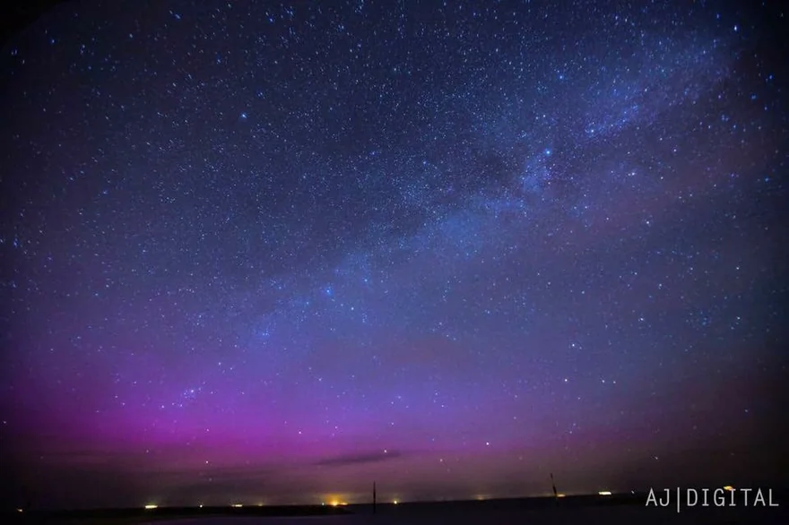 Star-filled night sky with a purple glow over the horizon