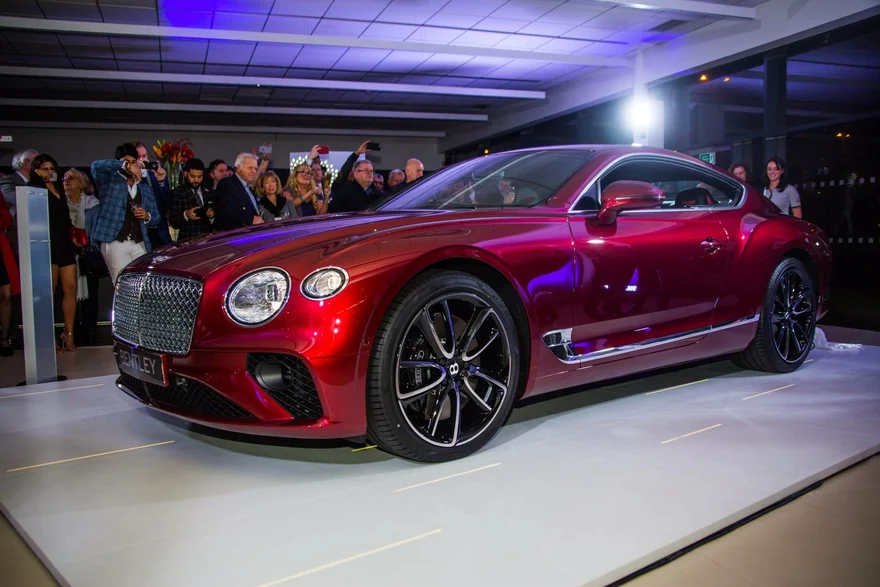 Red Bentley on display with visitors in the background